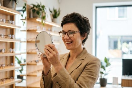 Femme d'une quarantaine d'années essayant des lunettes tendance en écaille dans une boutique d'optique moderne et chaleureuse